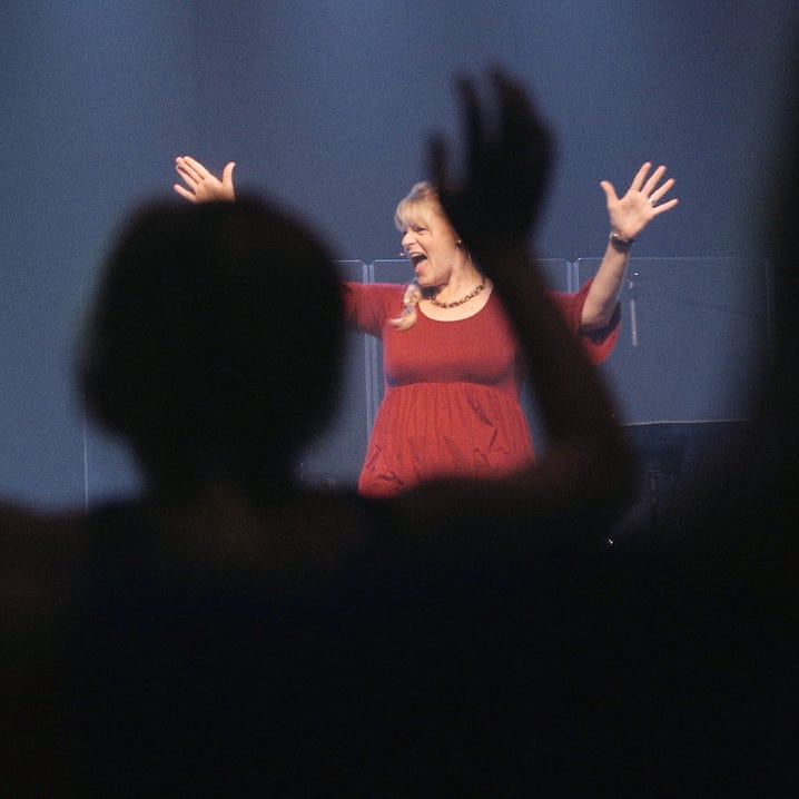Lisa Johnson speaks to a crowd as hands go up in the air
