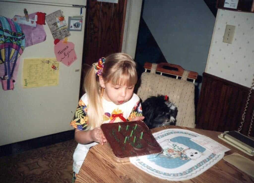 a young girl blows out  her birthday cake candles from this vintage photo