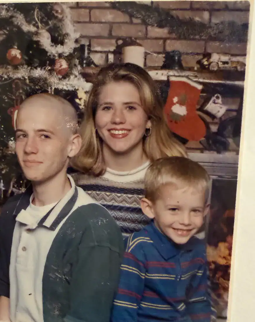 Matt with his sister and little brother in front of the Christmas tree