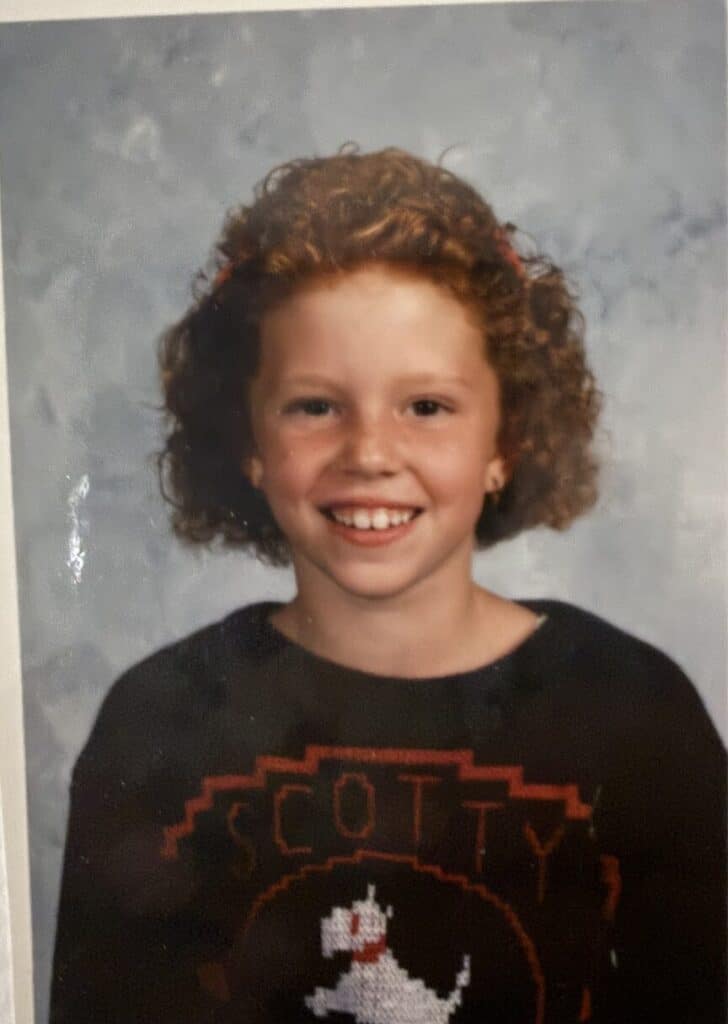 A school photo of a curly-haired girl in a Scotty dog sweater