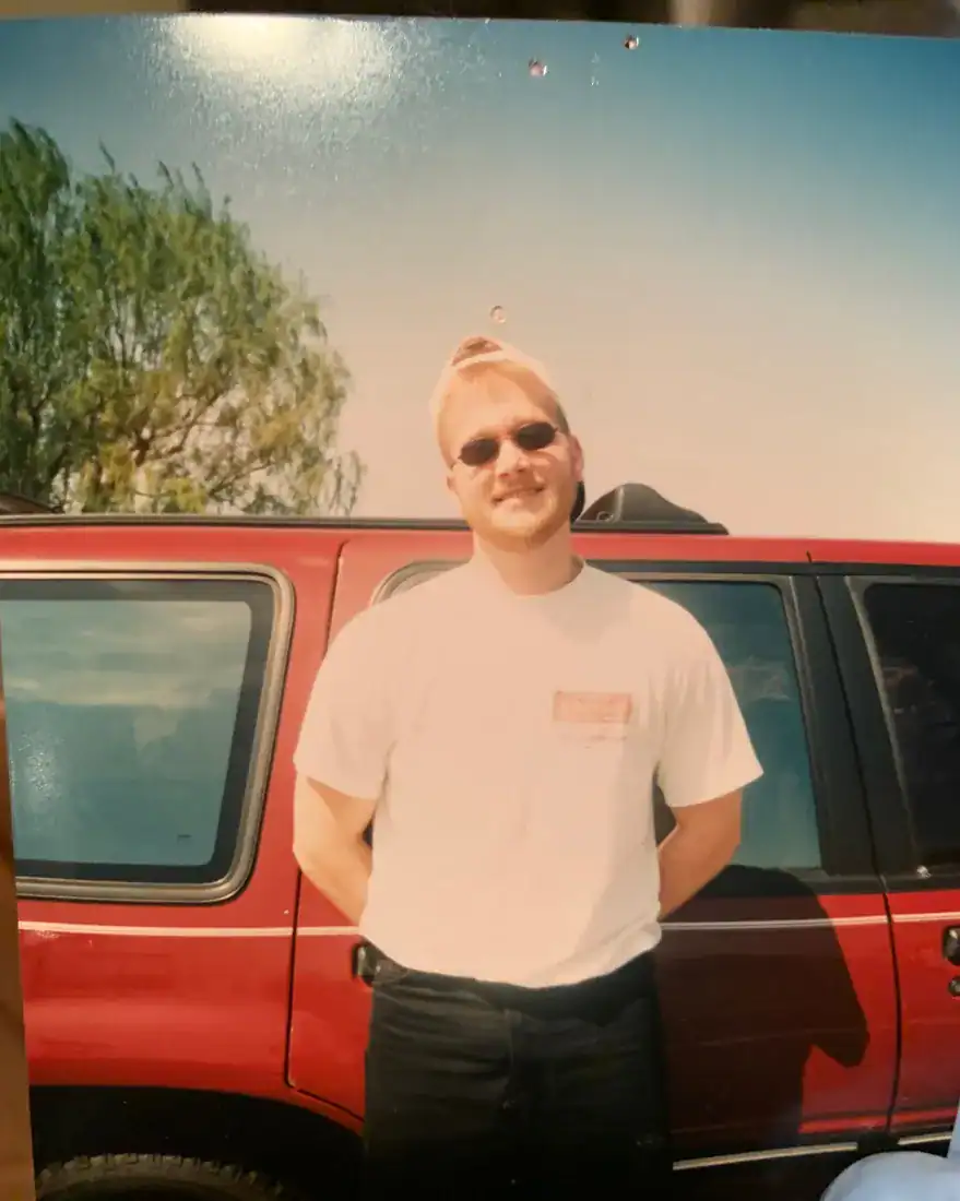 A young man in sunglasses with frosted tips in front of a red pickup truck
