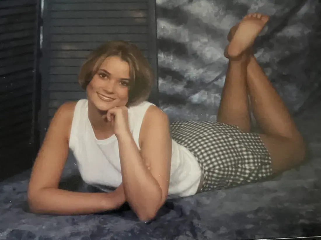 A 90s glamour-shot portrait on a mottled blue backdrop